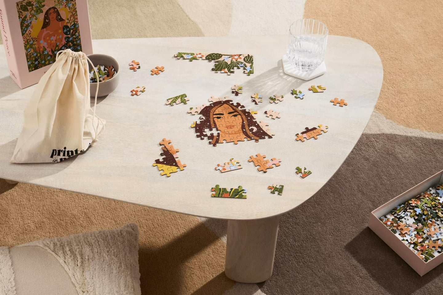 Jigsaw puzzle with a woman's face and nature-themed pieces on a table.